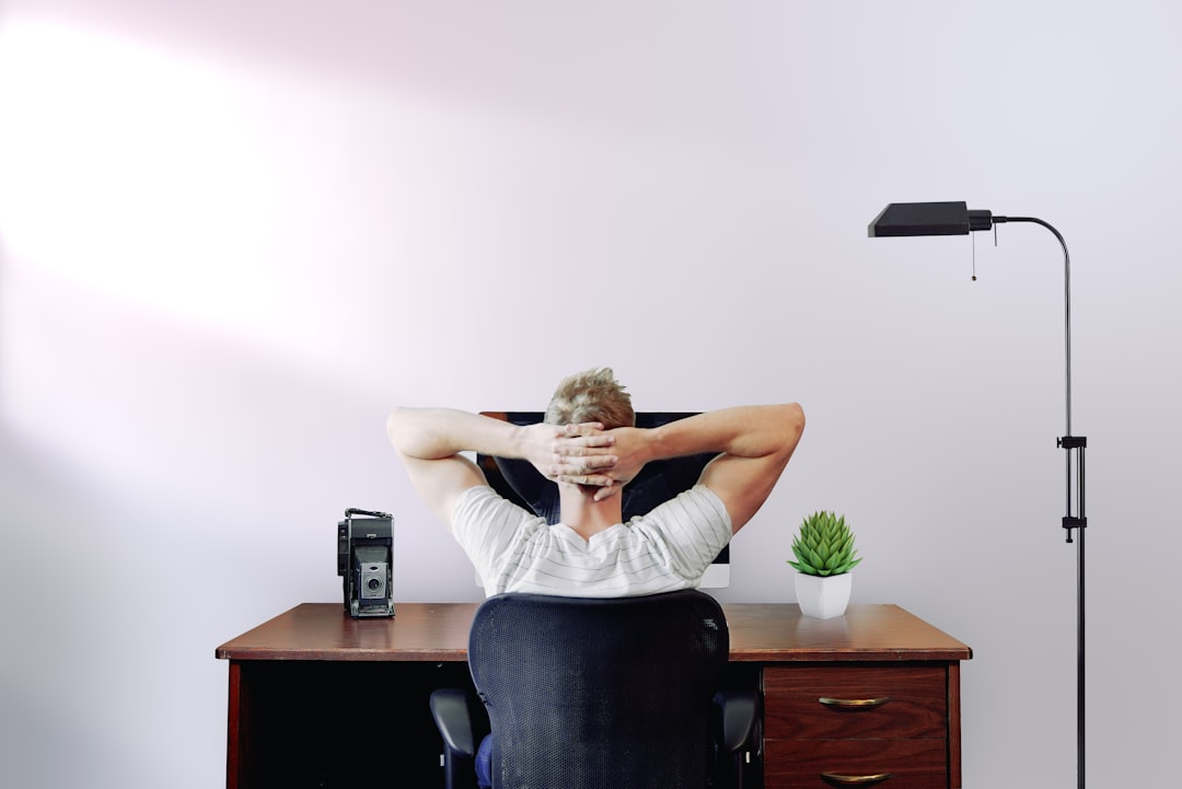 Ilustrasi: Man holding his head while sitting on chair near computer desk
