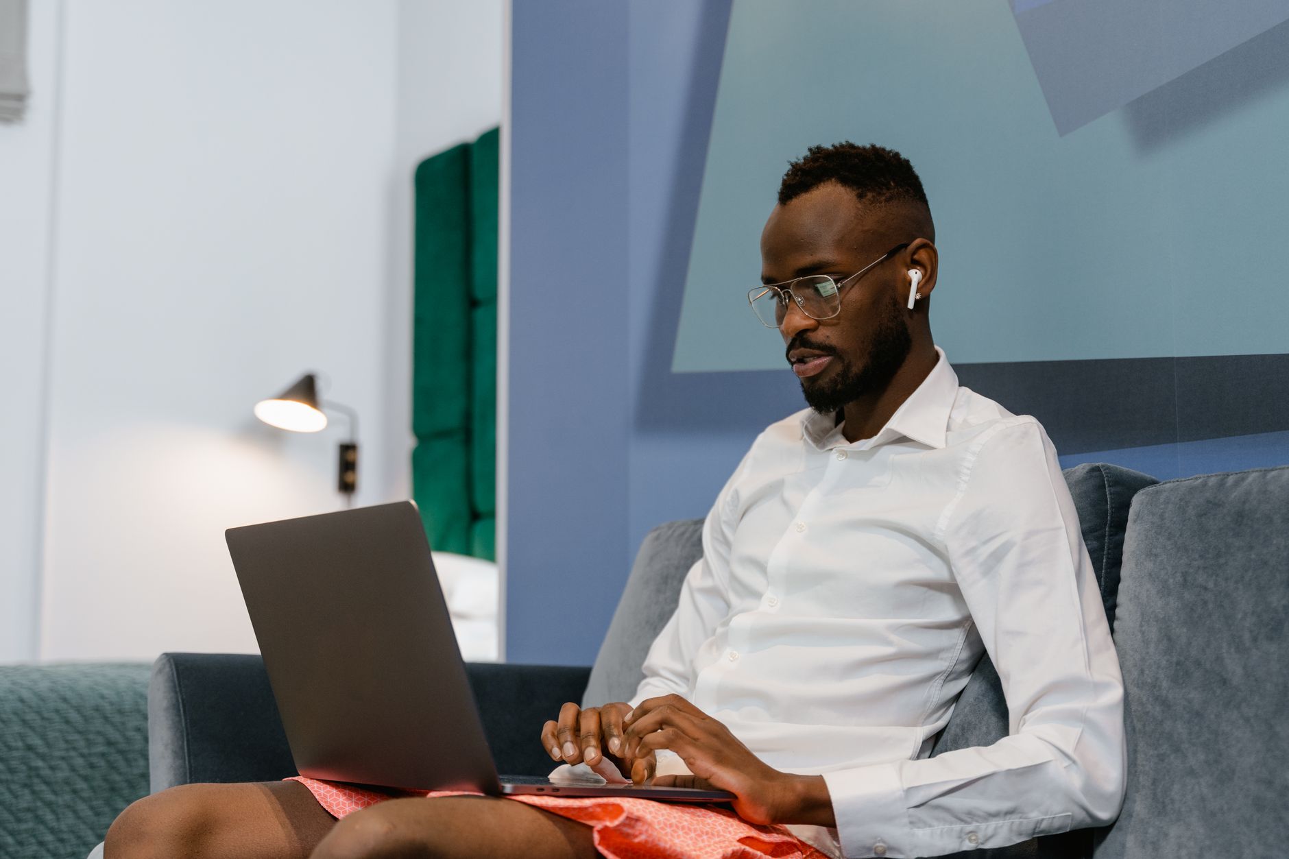 Ilustrasi: Man sitting on a sofa working remotely on a laptop at home.