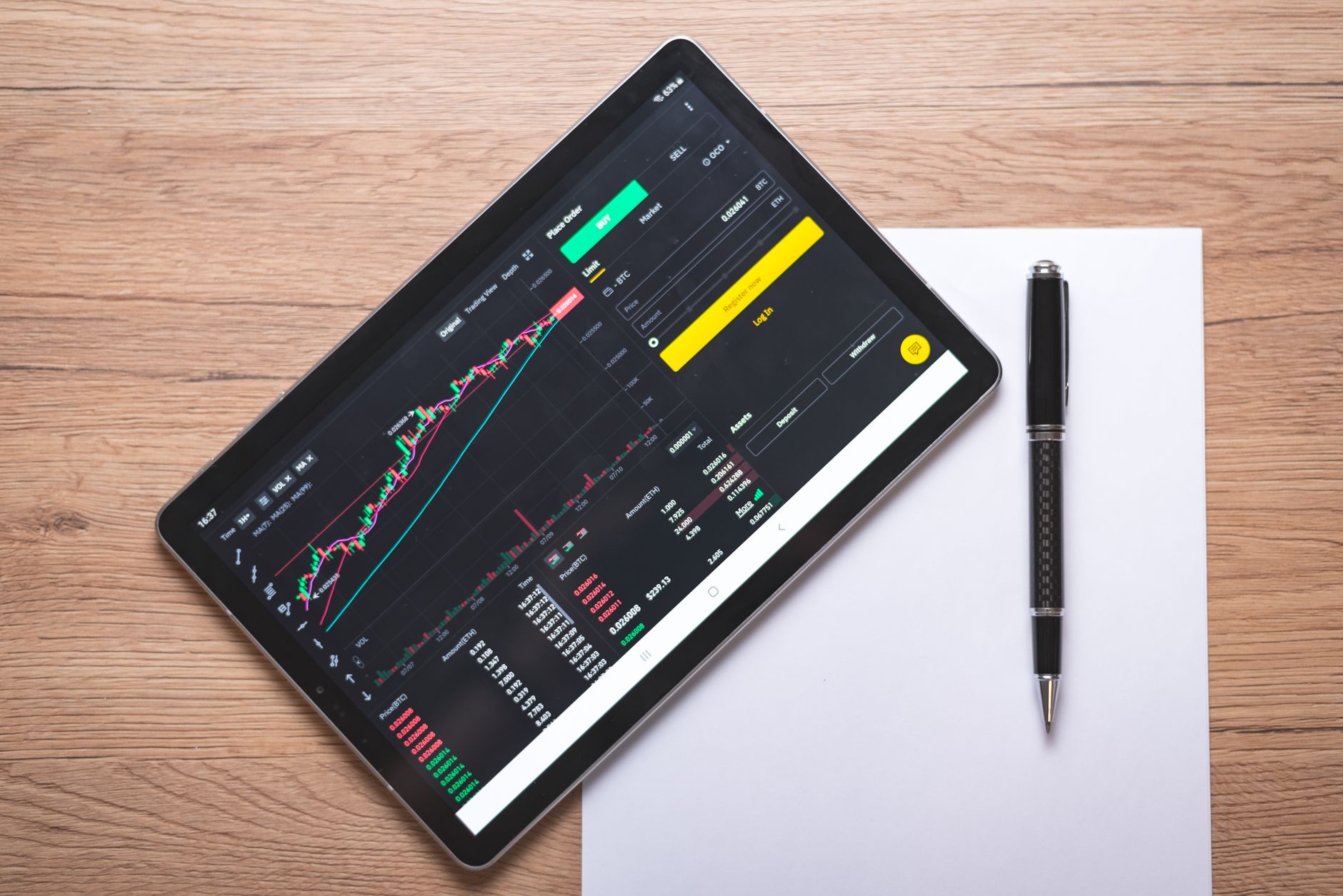 Ilustrasi: Overhead view of a digital tablet displaying stock market graphs and data on a wooden desk.