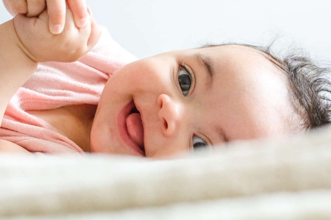 Ilustrasi: Baby in pink shirt lying on white textile