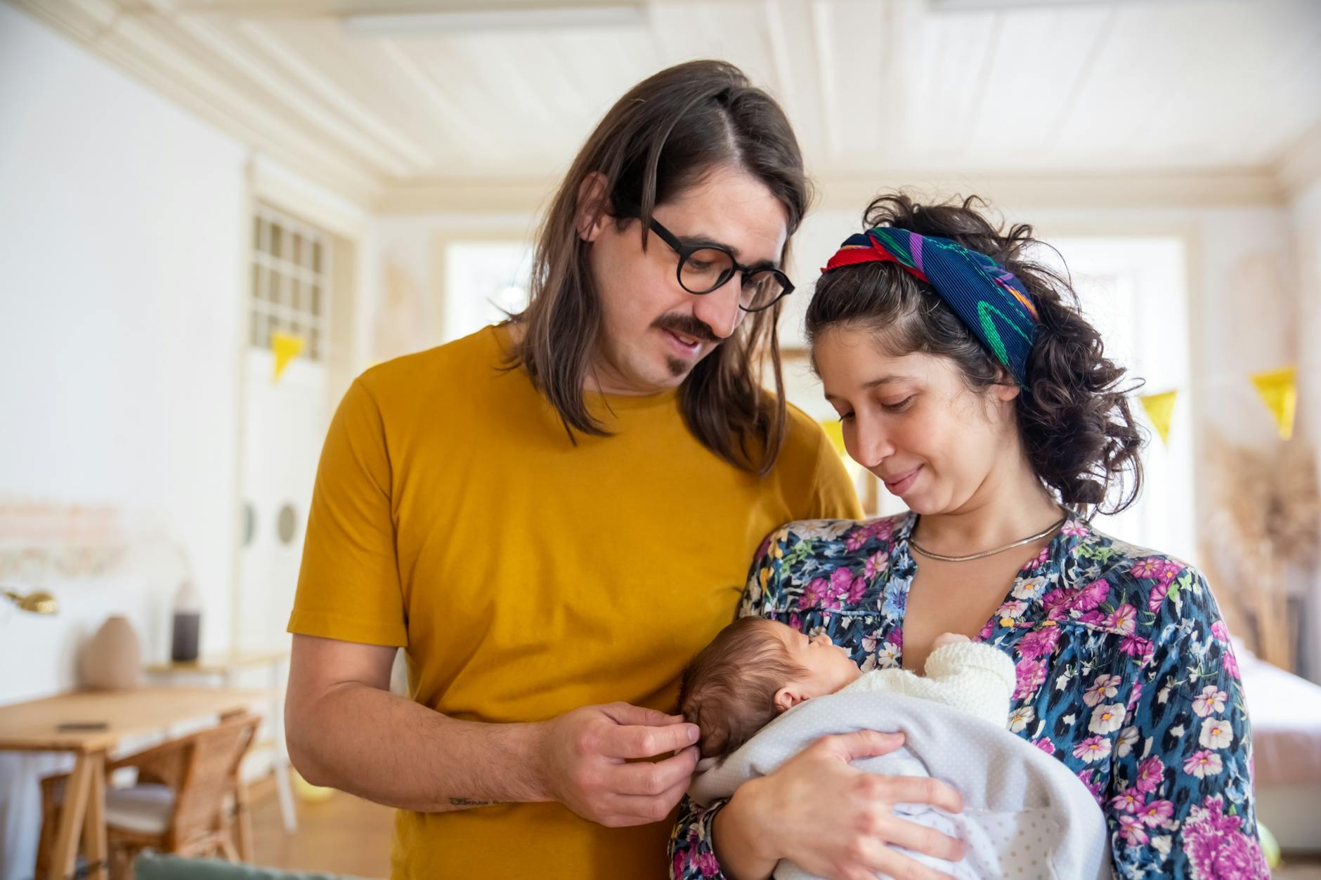 Ilustrasi: A tender family moment with parents holding their newborn baby indoors.