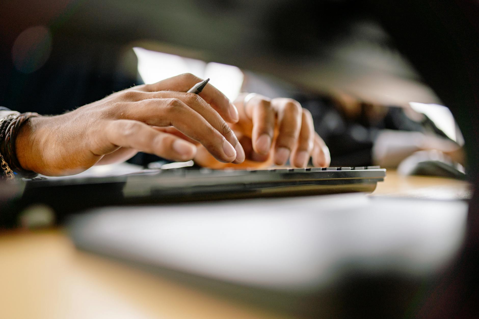 Ilustrasi: A detailed view of a person typing on a keyboard, emphasizing productivity and office work.