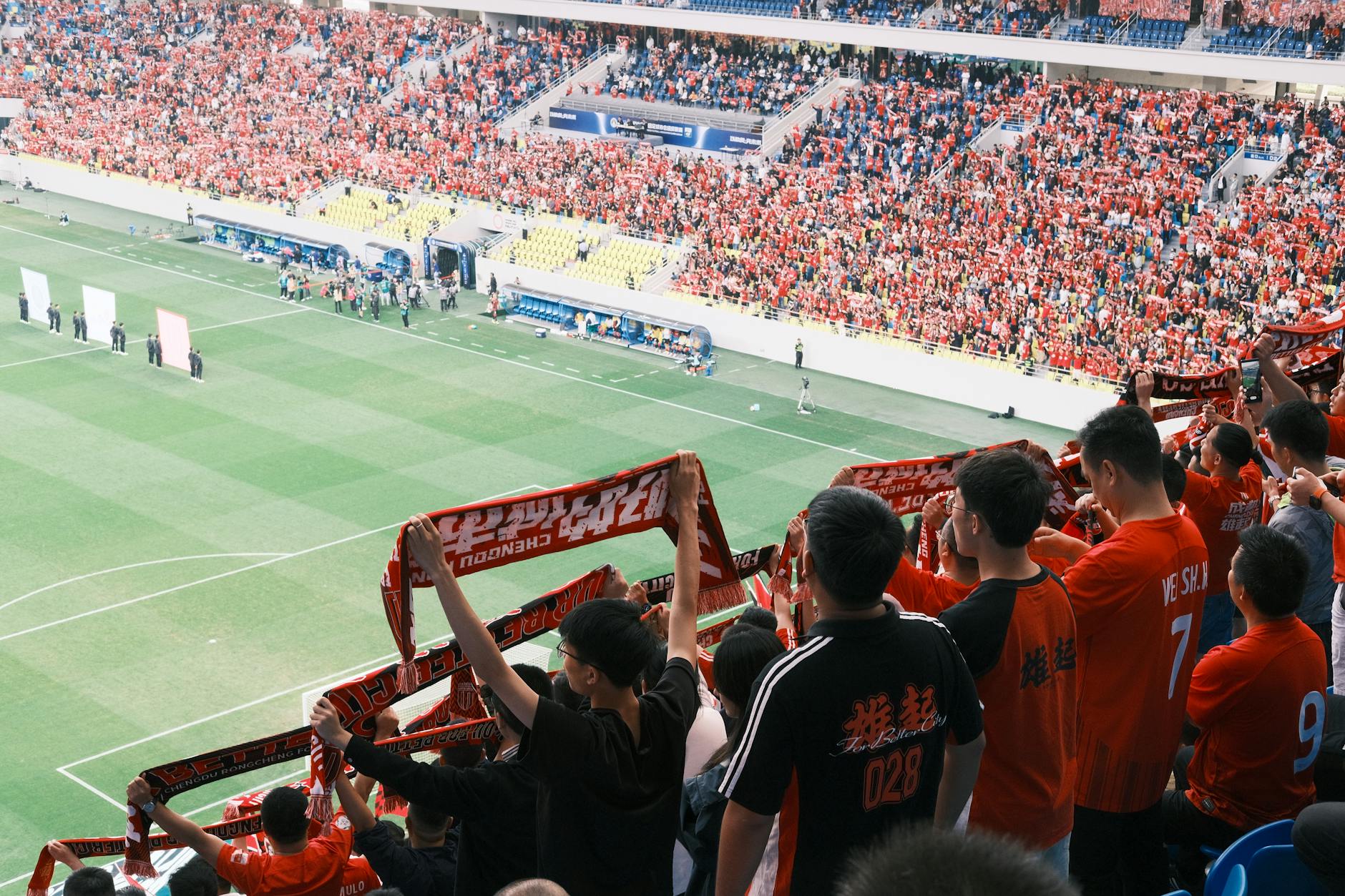 Ilustrasi: Of sepak bola in a stadion, waving scarves and cheering during a lively match.