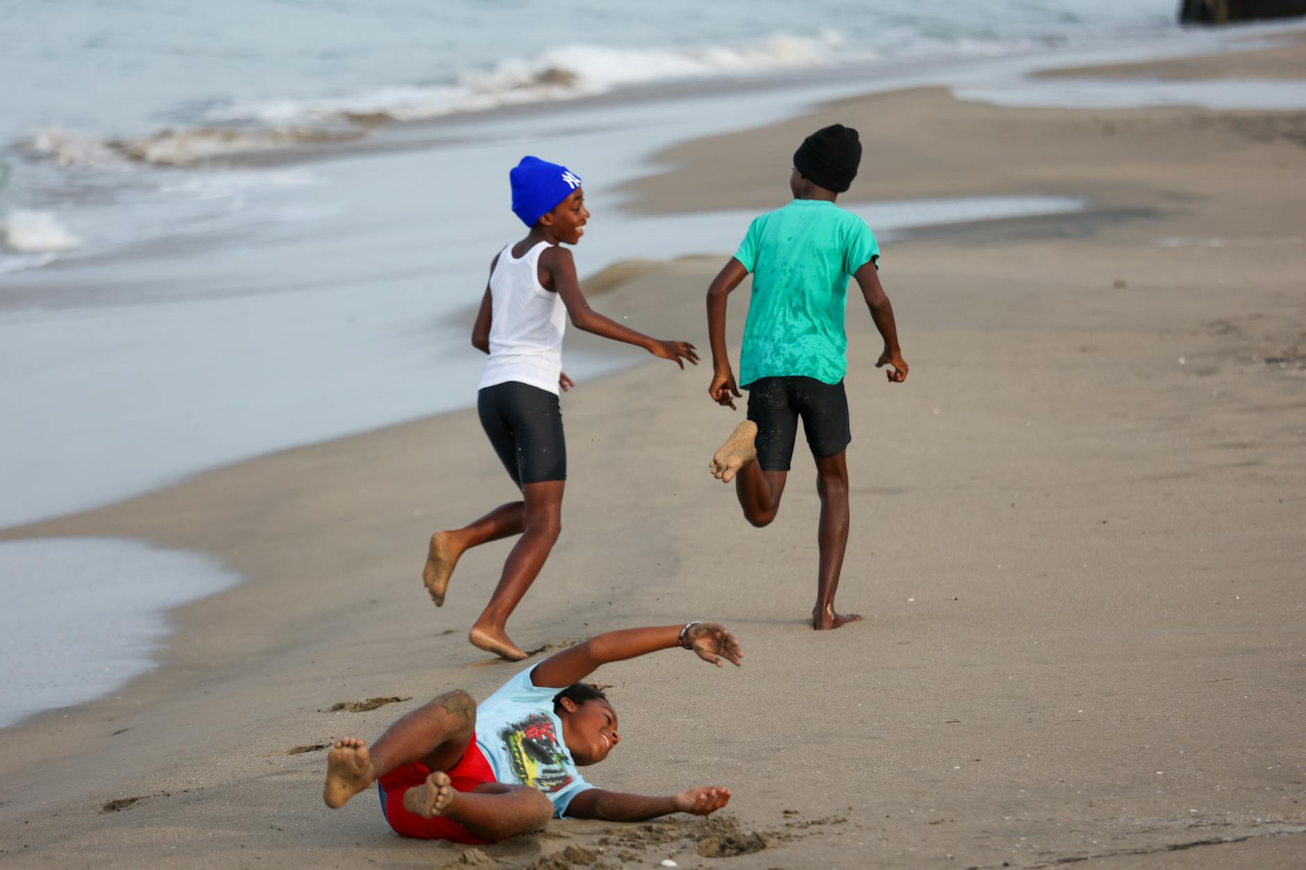 Ilustrasi: Three children bermain and running joyfully on the sandy beach in Charlestown, Saint Kitts and Nevis.