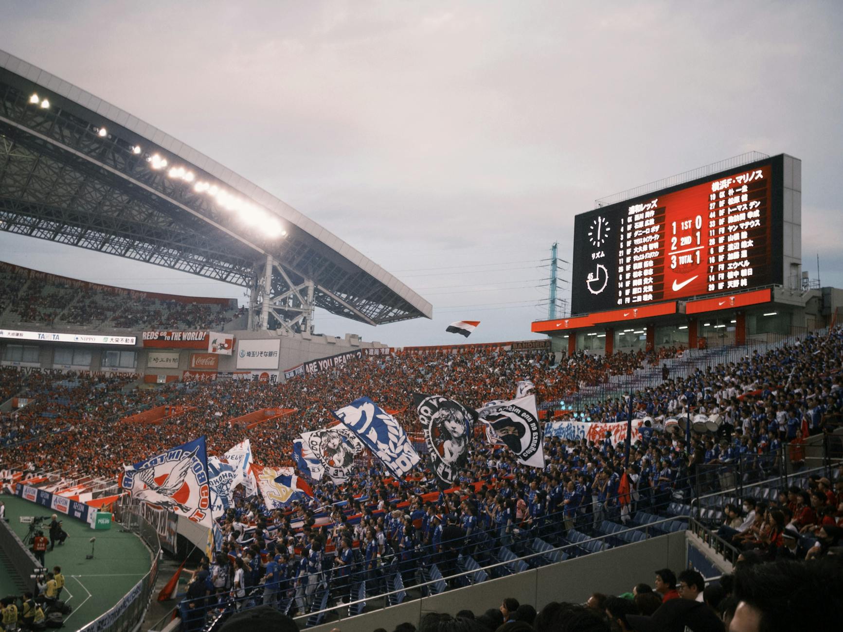 Ilustrasi: Energetic pertandingan sepak bola scene with cheering and colorful flags in a large stadion.