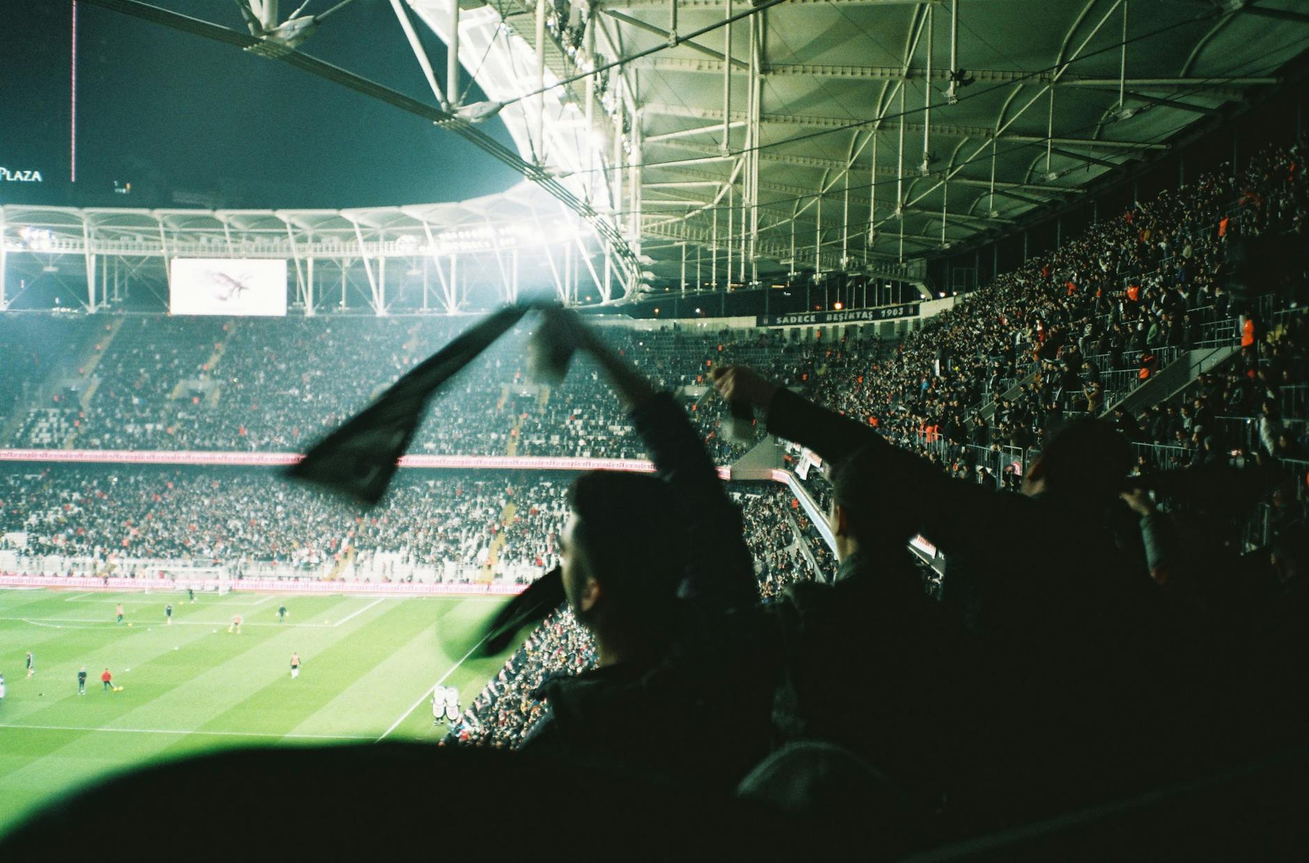 Ilustrasi: Exciting night pertandingan sepak bola with cheering in a brightly lit packed stadion.