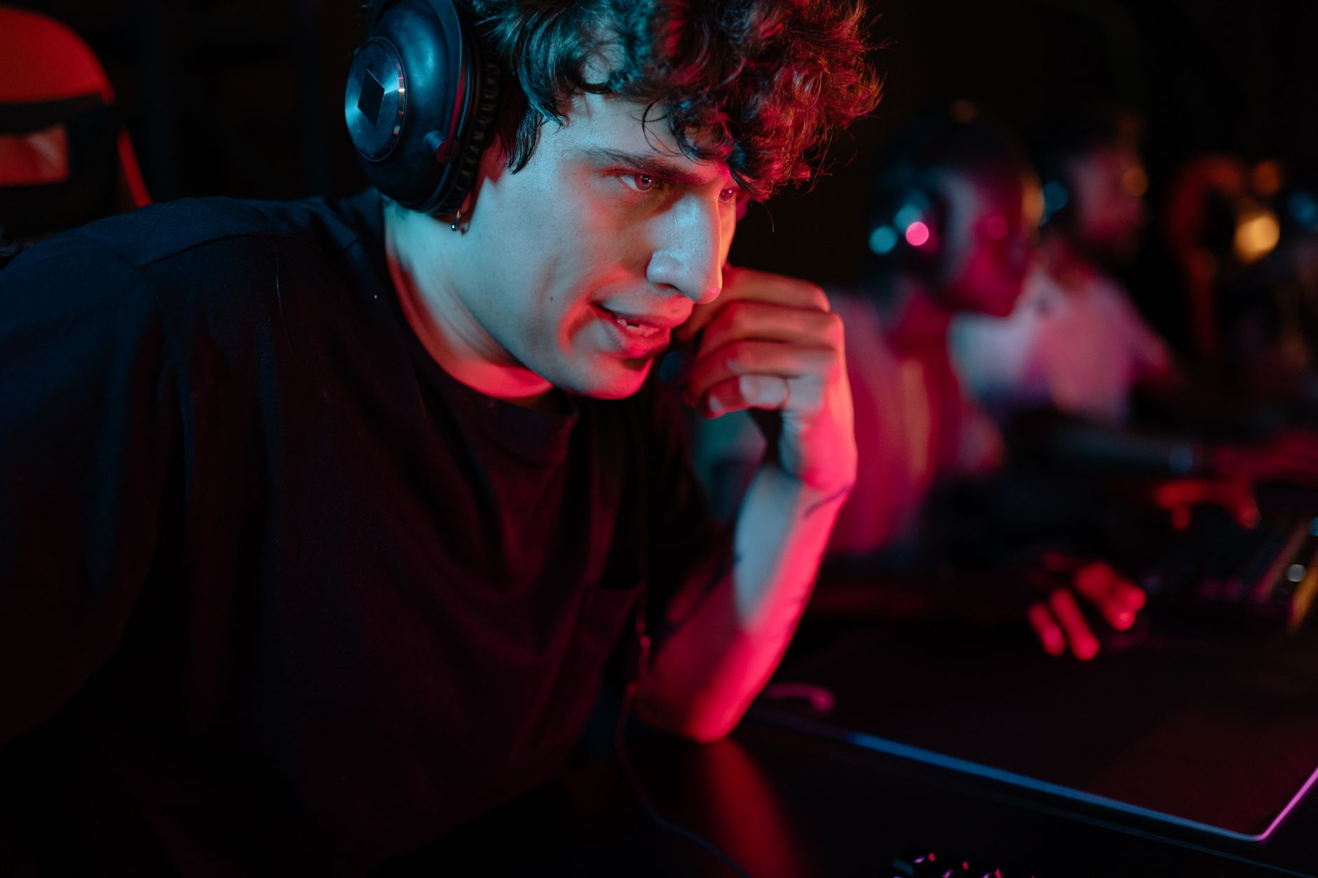 Ilustrasi: Close-up of a focused gamer wearing a headset in a dimly lit environment, immersed in an intense gaming session.